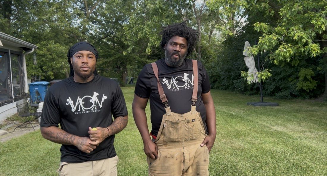Two V.O.V crew members in matching shirts and work overalls