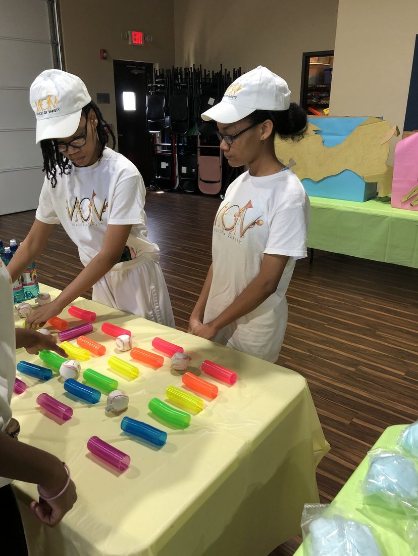 V.O.V youth volunteers running a carnival game table at a community day