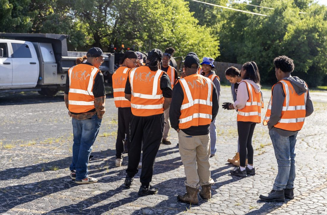 V.O.V work crew huddled up in orange safety vests before starting the job
