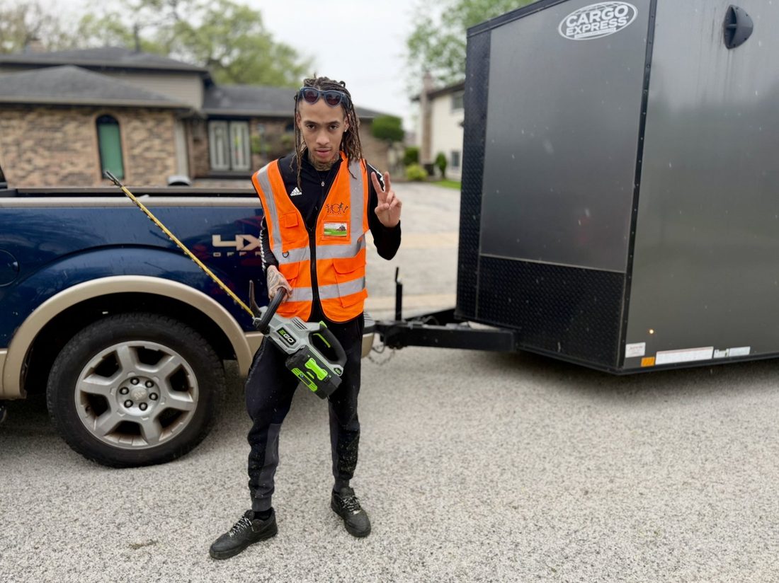 A V.O.V lawn crew member loading gear by the trailer