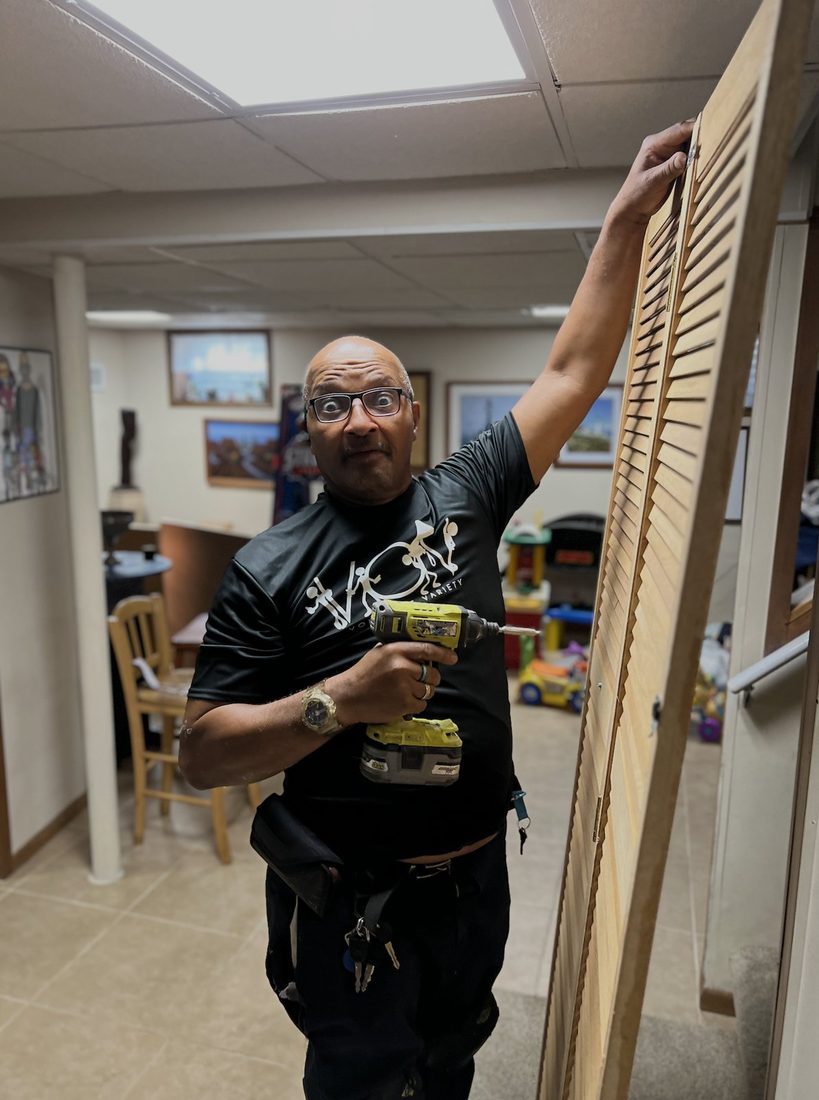 A V.O.V member hanging a louver closet door with his drill