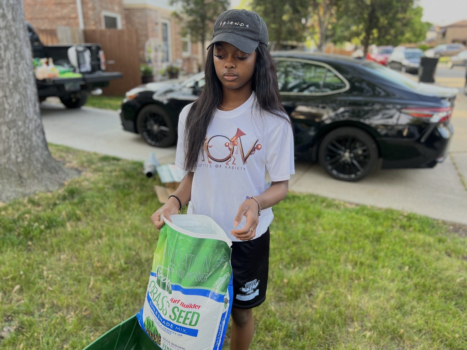 A V.O.V youth pouring grass seed for a neighbor&rsquo;s lawn