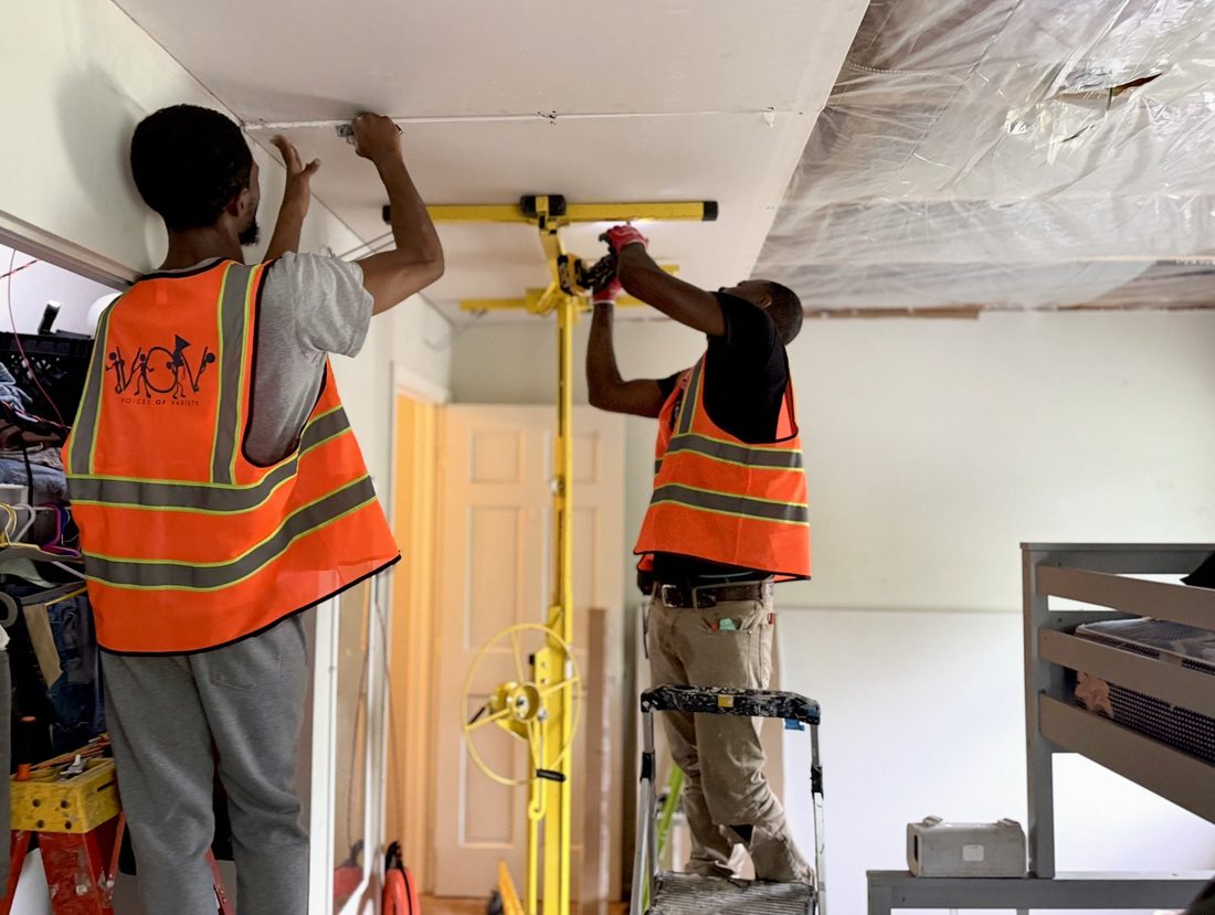 Two V.O.V crew members installing a ceiling with a drywall lift
