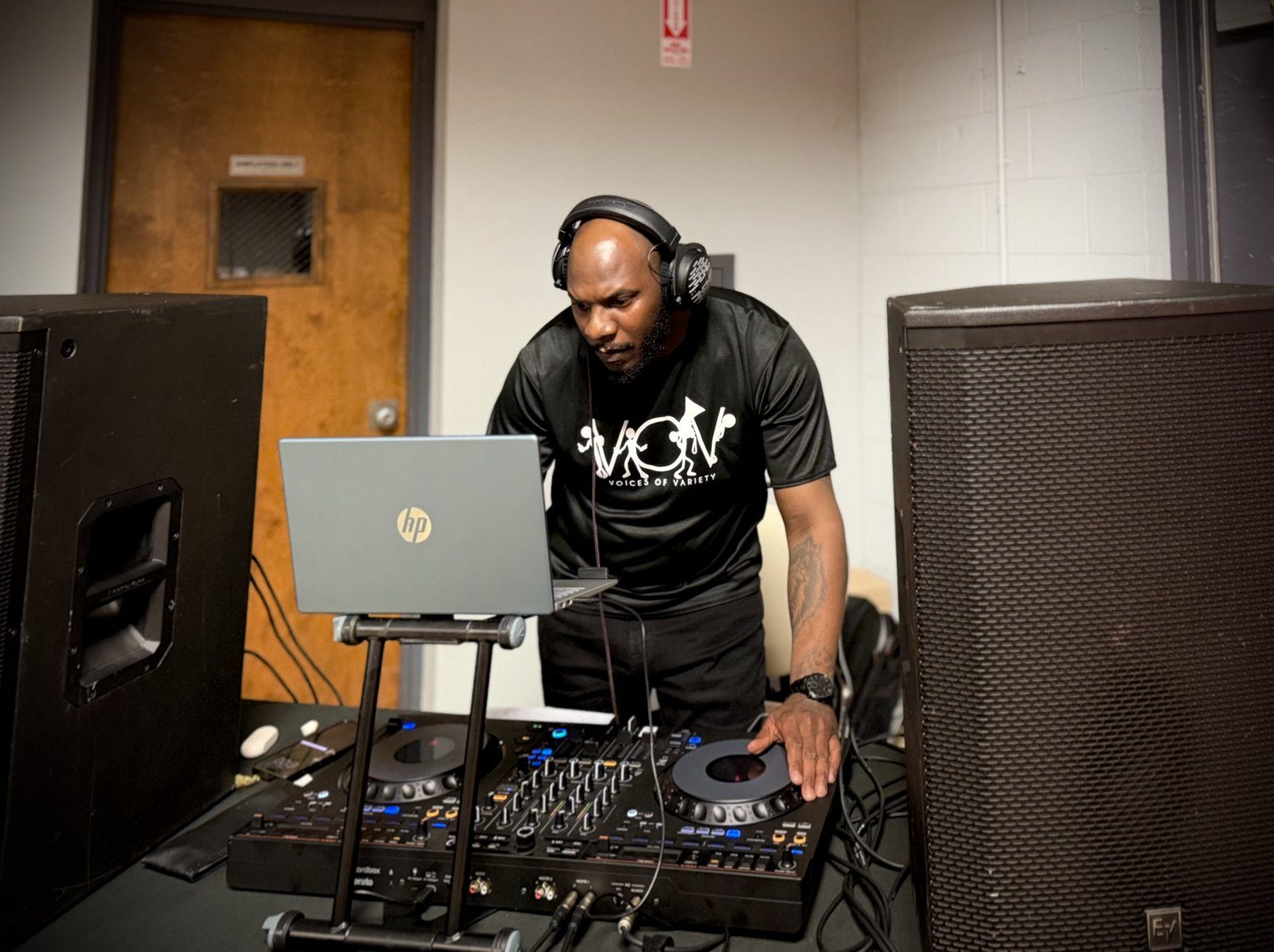 A V.O.V DJ on the decks in a Voices of Variety shirt