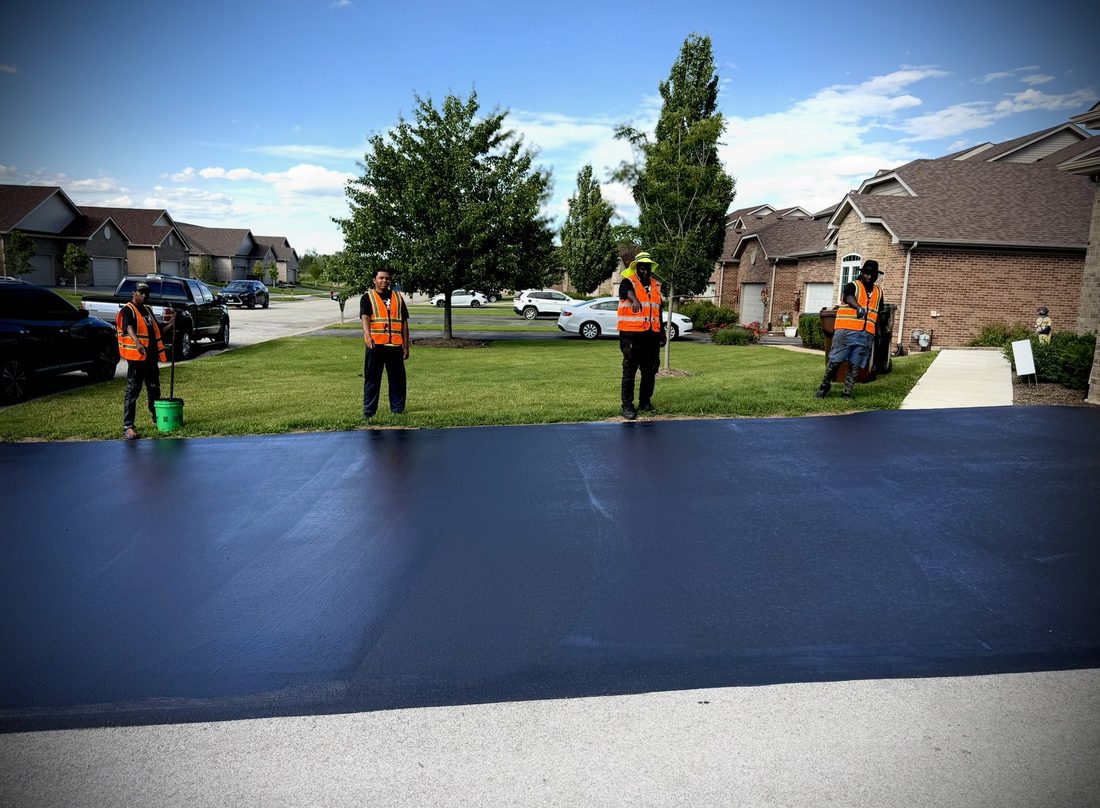 The crew standing around a freshly sealed driveway