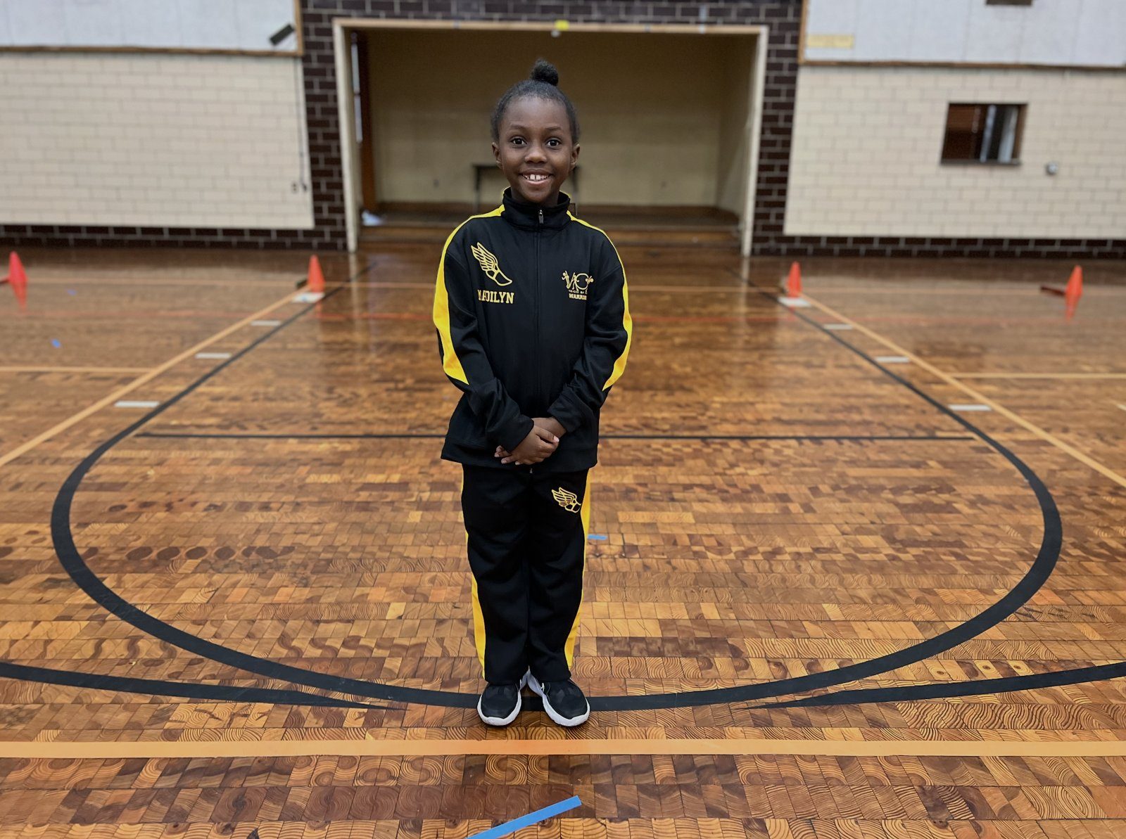 A young V.O.V member in her black and gold warmup suit